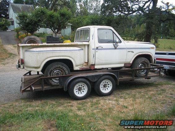 White pickup truck on a trailer, side view. Looks like a 1979 Ford F-150