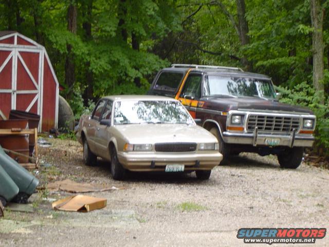 Brown and orange Ford Bronco parked next to a tan sedan