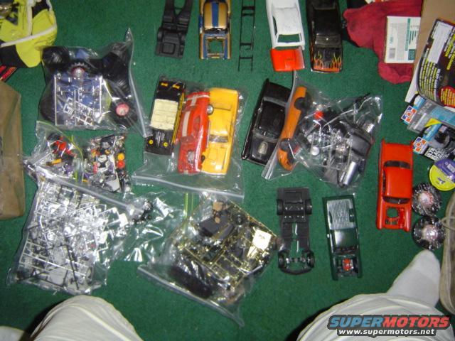 Collection of unassembled model car kits and loose parts spread on a green surface