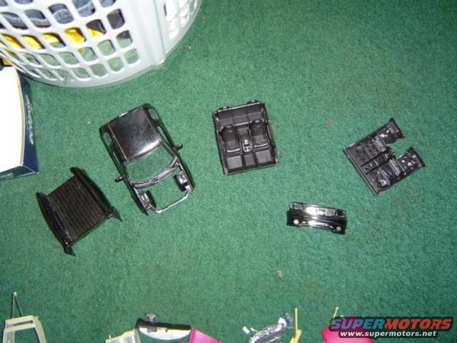 model car body, interior, and chassis parts scattered on green carpet