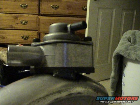 close-up of a fuel pressure regulator with hoses attached, sitting on a round metal object
