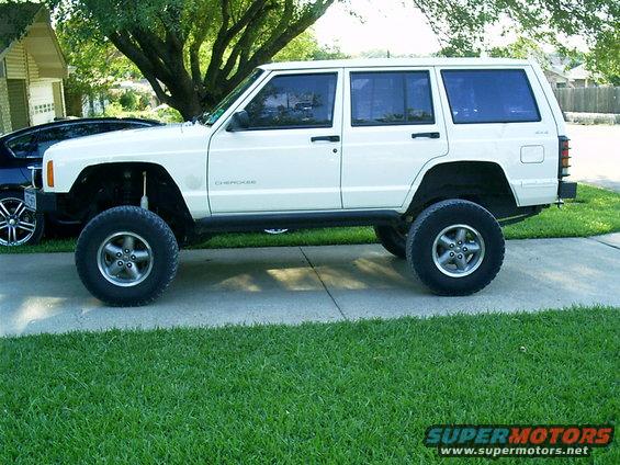 White Jeep Cherokee SUV with lifted suspension and off-road tires parked on a driveway