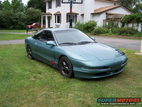 Teal 1994 Ford Probe parked on grass in front of a house