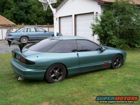 Teal 1994 Ford Probe with a large rear spoiler parked on grass