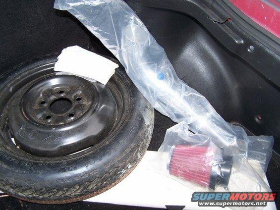 Spare tire and red air filter kit in trunk of red car