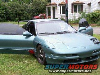 Teal 1994 Ford Probe with driver and passenger doors open, parked on grass