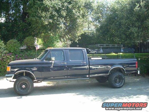 Crew cab pickup truck, possibly 1992 Ford F-250, with a roof rack and cargo in the bed
