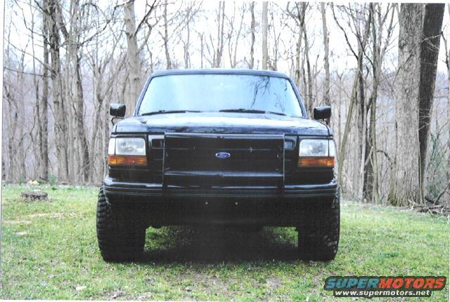 Front view of a black 1992 Ford Bronco parked in a wooded area
