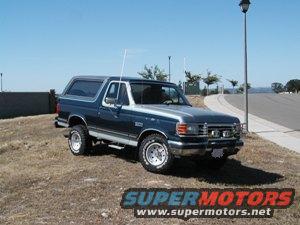 Dark blue and silver Ford Bronco parked on a grassy hill