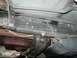 1989 Ford Bronco - Close-up view of the underside of a vehicle's frame, showing structural components and the transmission pan. The Supermotors.net logo is pr…