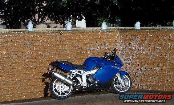 Blue motorcycle parked by a brick fountain