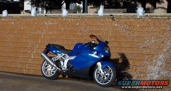 Blue 2005 BMW R1200CA ABS motorcycle parked in front of a brick wall with a waterfall