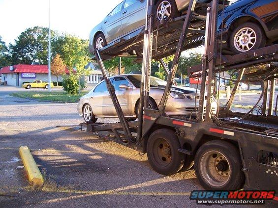 car carrier loaded with cars, one silver sedan in the middle