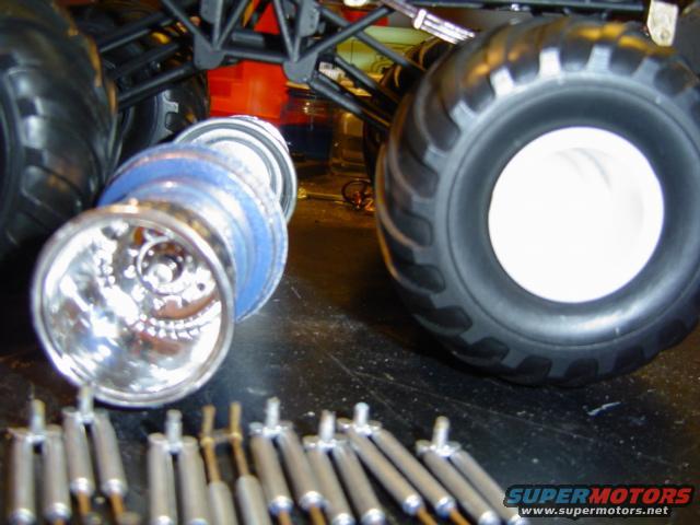 Monster truck tires, chrome rims, and shock absorbers laid out on a workbench