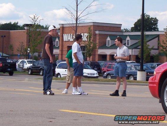 People gathered in a parking lot in front of a Walmart