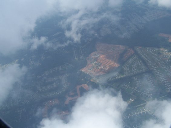 aerial view of suburban neighborhoods with some construction sites, seen through clouds