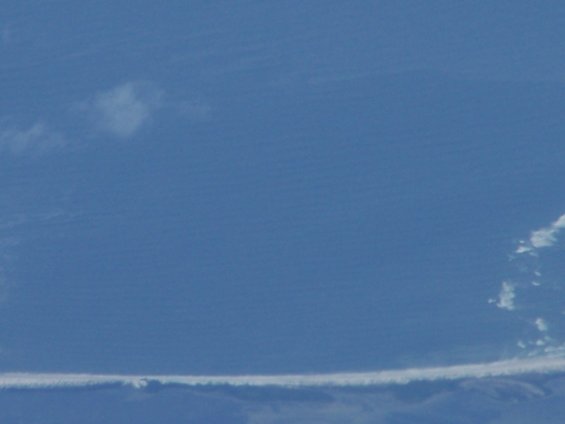 Blue sky with a long, thin cloud formation near the bottom and a few smaller clouds higher up