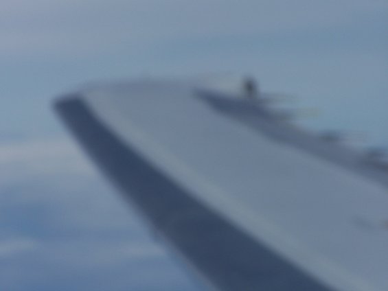 Airplane wing against a blue sky with clouds