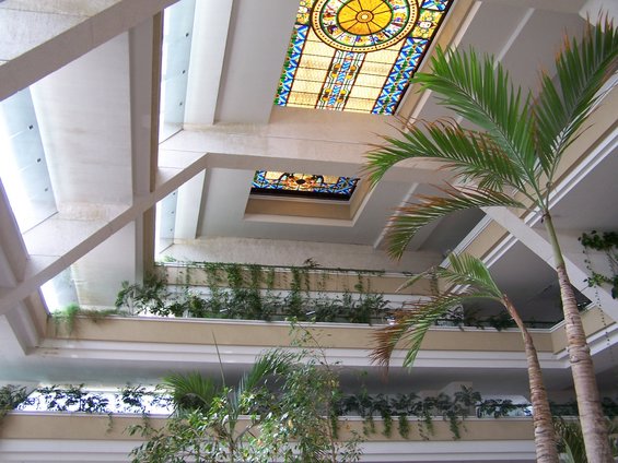 Interior atrium with multiple levels, plants, and stained glass skylights