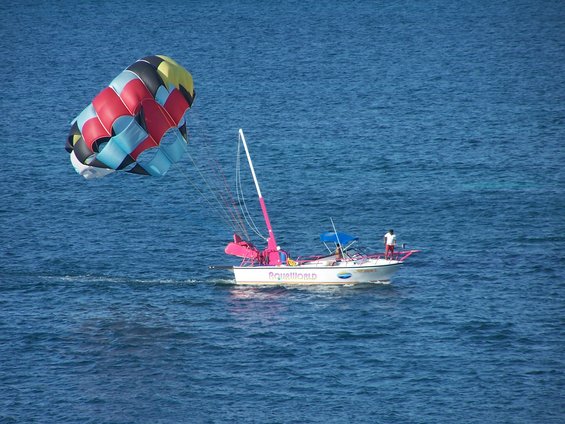 Boat with 'Aqua World' text on side, pulling a colorful parasail
