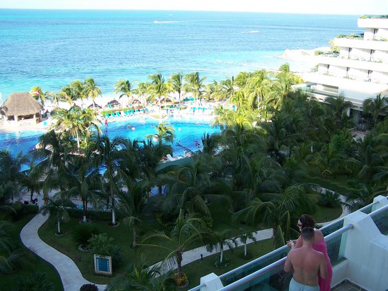 Resort pool and beach area with palm trees and ocean in the background
