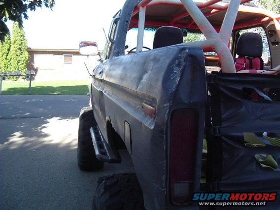 1979 Ford Bronco rear quarter panel with dents and roll cage visible inside