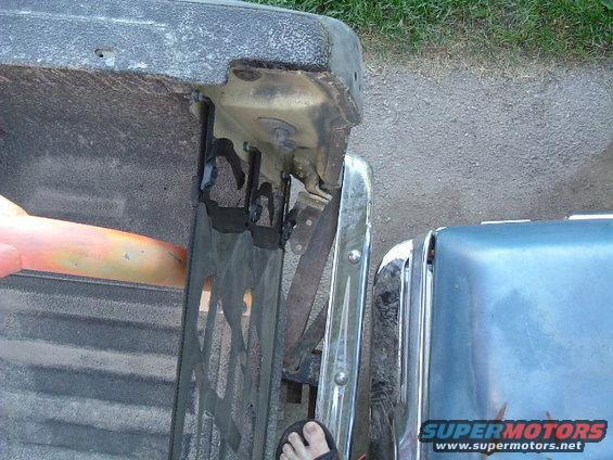 Close-up of a truck's tailgate and bumper, with another vehicle's fender visible next to it