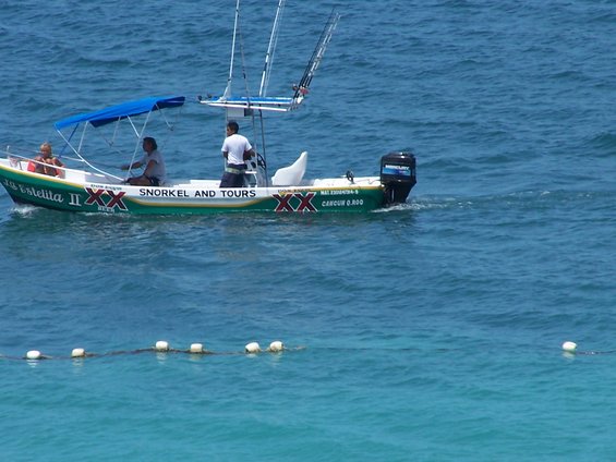 Boat named La Estelita II with 'SNORKEL AND TOURS' text, carrying three people and fishing rods