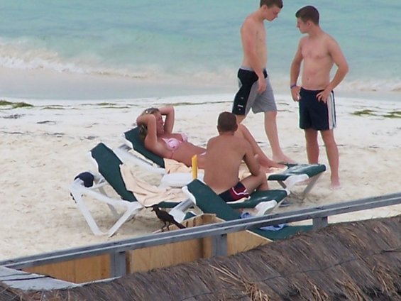 People relaxing on beach chairs on a sandy beach with the ocean in the background