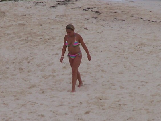 Woman in a colorful bikini walks across a sandy beach