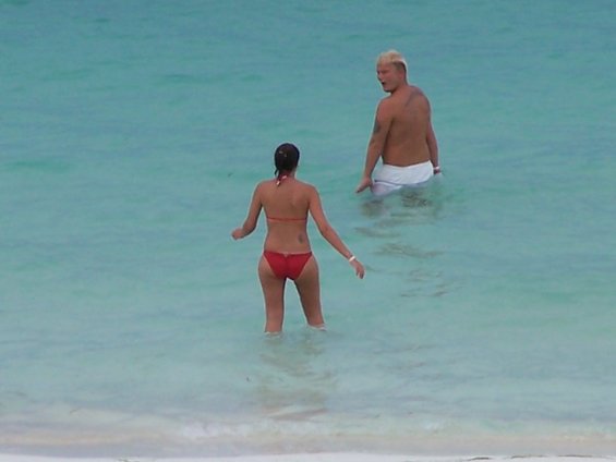Woman in red bikini and man in white shorts wading in turquoise water