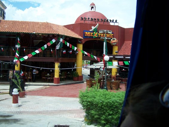 Restaurant with red dome and 'Mex Treme' sign, decorated with Mexican flags
