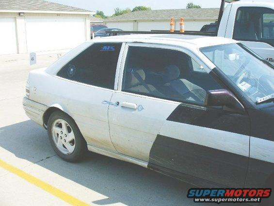 Side view of a white and black two-door coupe with tinted windows and a roof rack