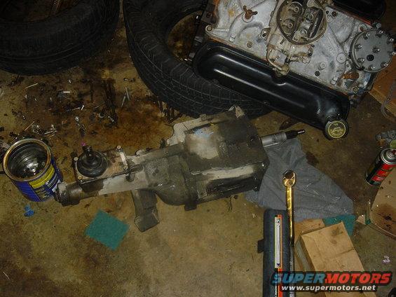 Engine block, transmission, and tires on a dirty garage floor with tools