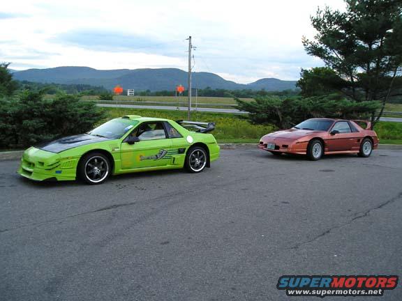 Two 1984 Pontiac Fieros parked on asphalt, one lime green with black hood, the other copper orange