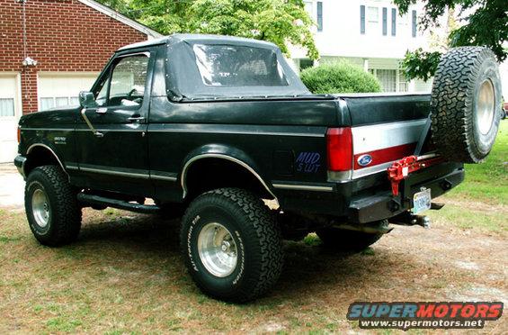 1988 Ford Bronco with soft top, spare tire mounted on rear bumper, and aftermarket wheels
