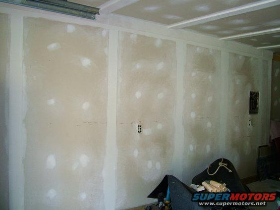 Room interior with unfinished drywall, electrical boxes, and a Supermotors.net logo visible