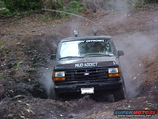 Black SUV with "MUD ADDICT" on the hood navigating a muddy trail