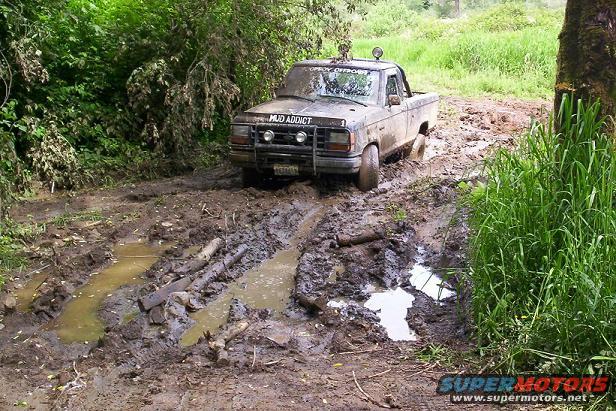 1992 Ford Ranger stuck in mud on a trail, with 'MUD ADDICT' decal on hood
