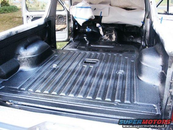 Truck bed interior with spray-in liner applied. Doors are open, showing interior components
