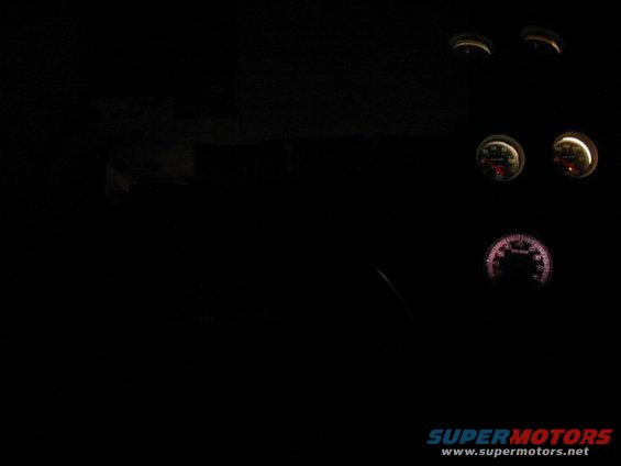 Car interior with several illuminated gauges visible in the dark