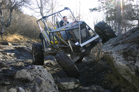Off-road buggy with roll cage climbing over rocks