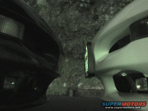 Close-up of the front ends of two cars, one black and one white, parked closely together