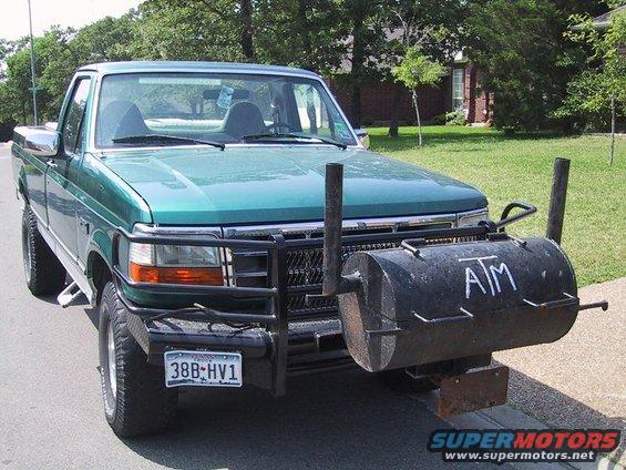 Green pickup truck with custom smoker grill on front bumper, license plate 38B-HV1