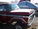 1979 Ford Bronco - A red pickup truck is parked outdoors next to a covered boat.