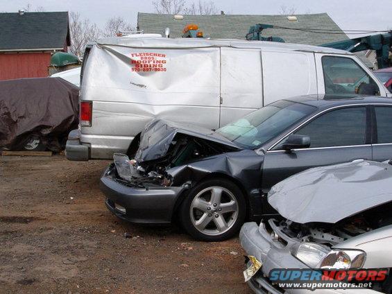Front view of a dark gray 2003 Acura TL with severe front-end damage