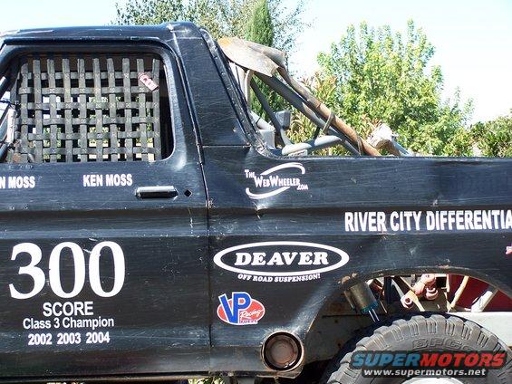 Side view of a black off-road race truck with number 300 and various sponsor decals