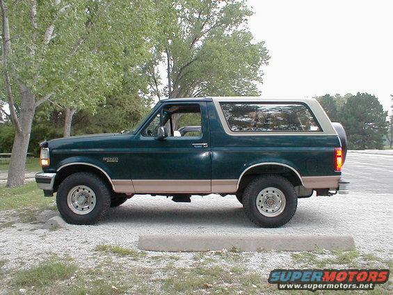 Green 1994 Ford Bronco side view with tan trim and spare tire on rear