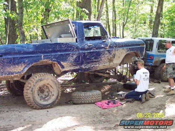 Blue 1977 Ford F-150 with lifted suspension and off-road tires, being worked on outdoors