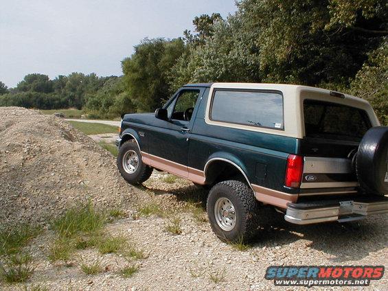 1994 Ford Bronco parked on a dirt path with trees in background